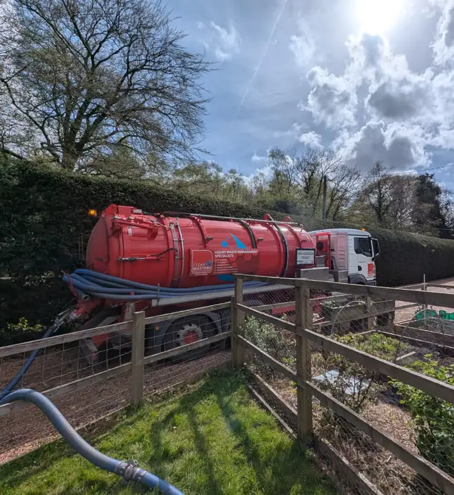 Clearmasters tanker on a rural driveway, with its hose run through the garden to the tank